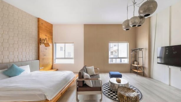 A modern hotel room with a bed, a sofa, a small round table, and a TV. - We Share Hostel (Tainan)