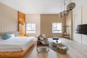 Una habitación de hotel moderna con una cama, un sofá, una pequeña mesa redonda y un televisor.