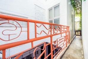 A corridor with a red railing, white walls, and a window. - We Share Hostel (Tainan)