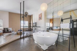Un baño moderno con una bañera independiente, cabina de ducha con mampara de vidrio y un espejo grande.