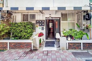 A hotel entrance with a brick pathway, a welcome mat, and potted plants. - We Share Hostel (Tainan)