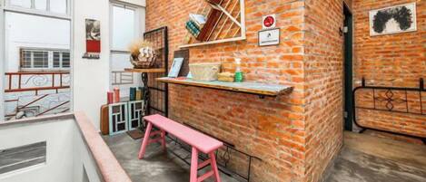A room with a brick wall, a bench, and a shelf with various items.