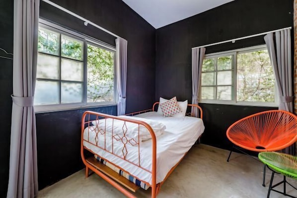 Une chambre à coucher avec un lit, deux fenêtres et une chaise.