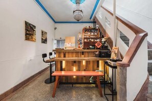 A bar area with a wooden counter, stools, and a bench. - We Share Hostel (Tainan)