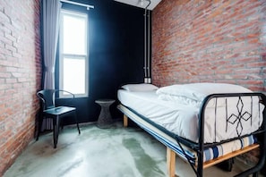 Une pièce comprenant un lit, une chaise, une petite table et une fenêtre.