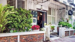 A building with a brick facade, a welcoming sign, and various potted plants. - We Share Hostel (Tainan)