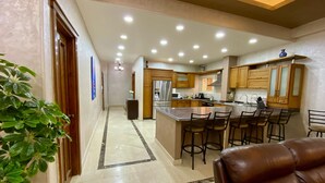 A modern kitchen with a central island, bar stools, and wooden cabinets. - Luxurious Villa Serene Garden New Cairo (New Cairo)