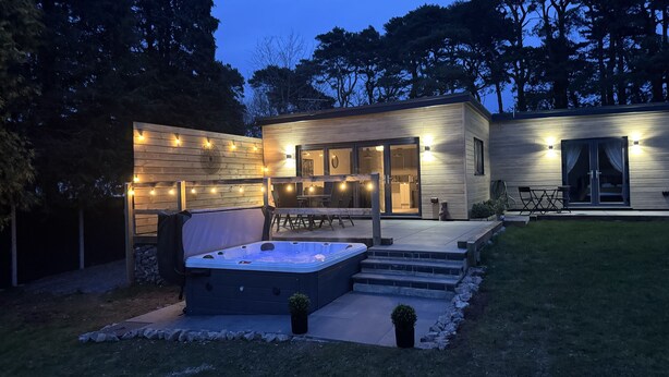 Een modern huis met een jacuzzi, zitplaatsen buiten en lichtjes.
