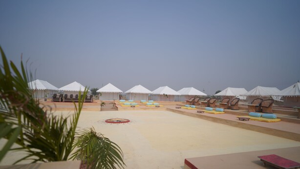 A series of white tents with attached lounge chairs and sofas, arranged in rows on a flat surface. - Teela Jaisalmer Luxury Desert Swiss Tent (Jaisalmer)