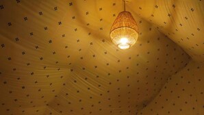 A room with a bed, a bedside table, a lamp, and a hanging light fixture. - Teela Jaisalmer Luxury Desert Swiss Tent (Jaisalmer)