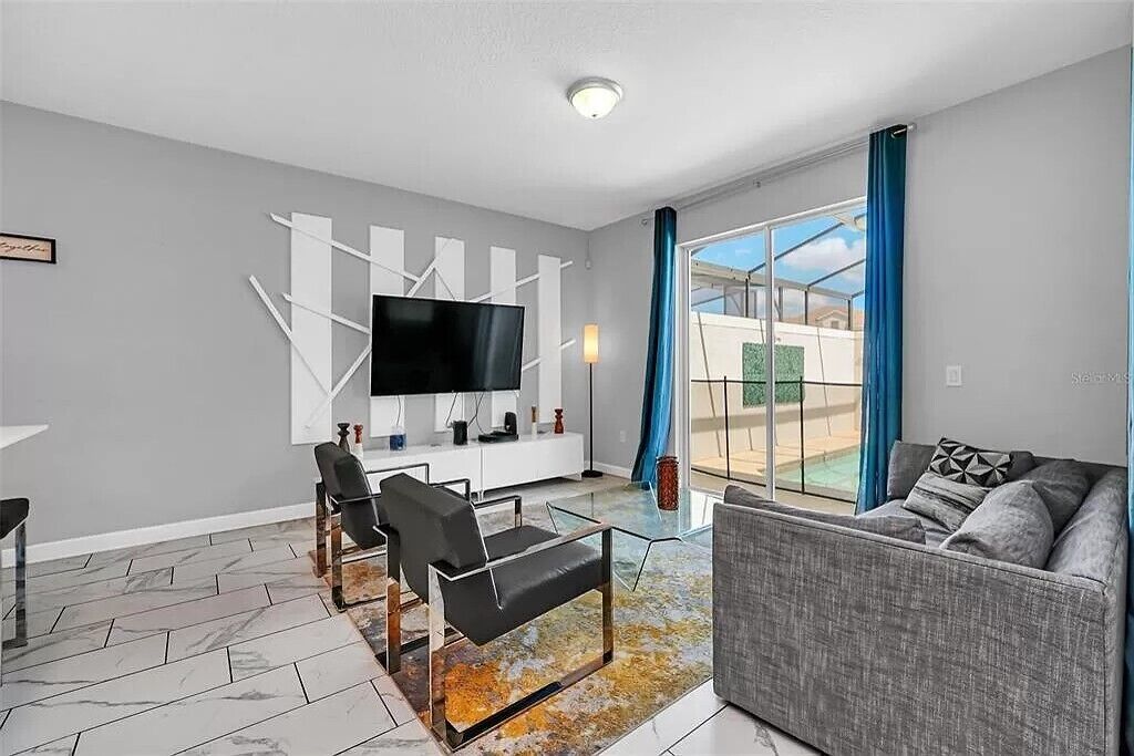 A modern living room with a flat-screen TV, a sofa, a coffee table, and a glass partition.