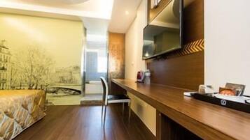 A modern hotel room with a wooden bar, a flat-screen TV, and a view of a cityscape.