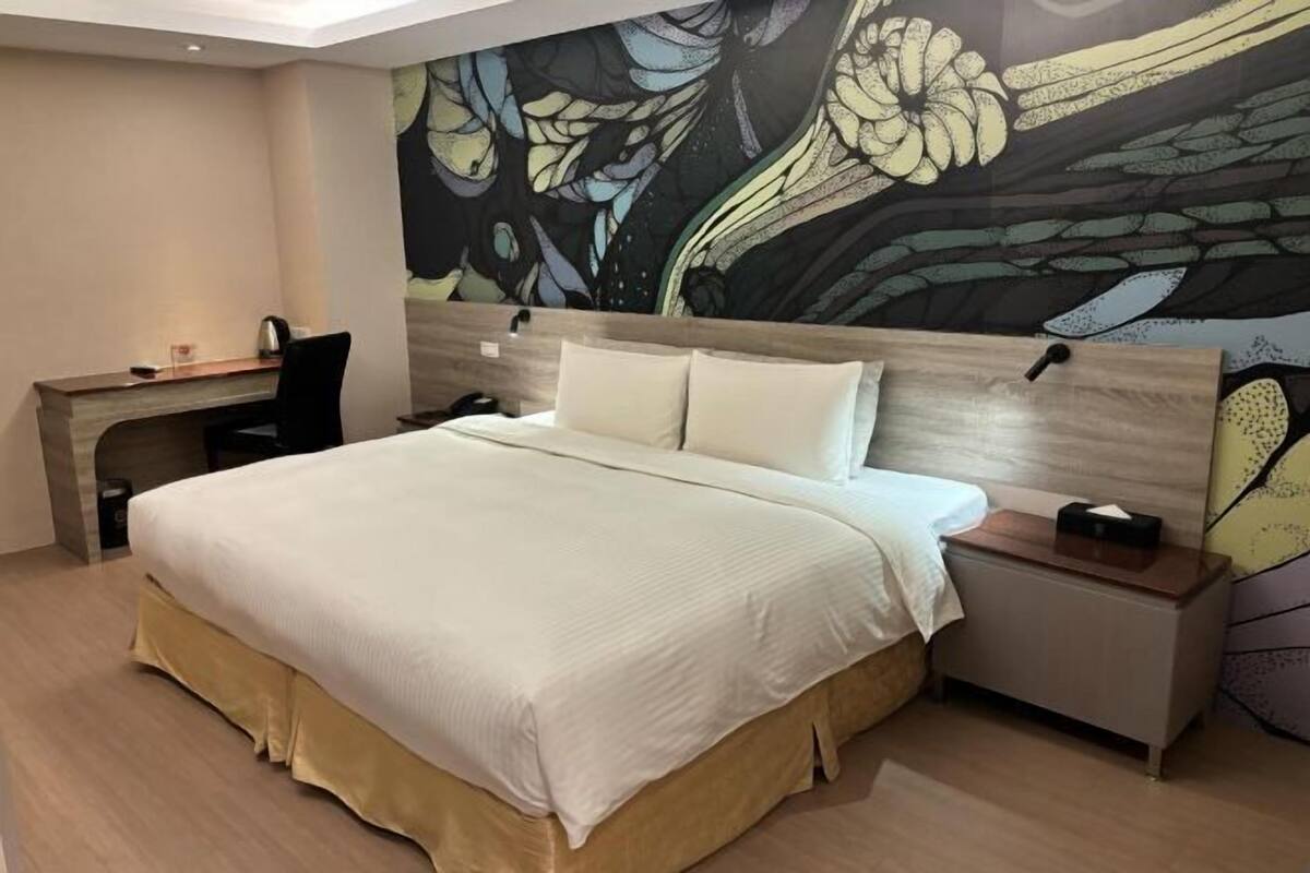 Un dormitorio con una cama, un escritorio y una mesita de noche.