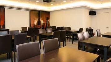 A conference room with tables and chairs, a projector screen, and a whiteboard.