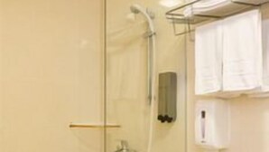 Un baño con cabina de ducha de vidrio, inodoro y barra para toallas.