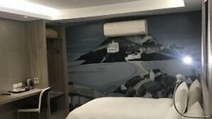 Una habitación de hotel con una cama, un escritorio y un mural de un paisaje montañoso.