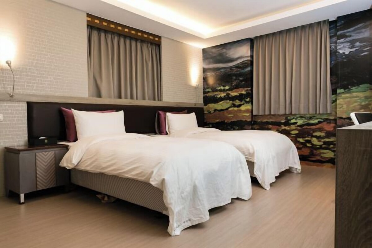 A double bed with a headboard, a nightstand, a wall-mounted TV, and a mural with curtains.