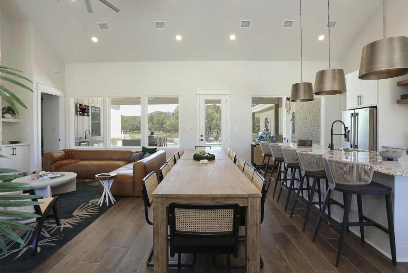 A spacious dining area with a long wooden table, multiple chairs, and a kitchen area with modern appliances.