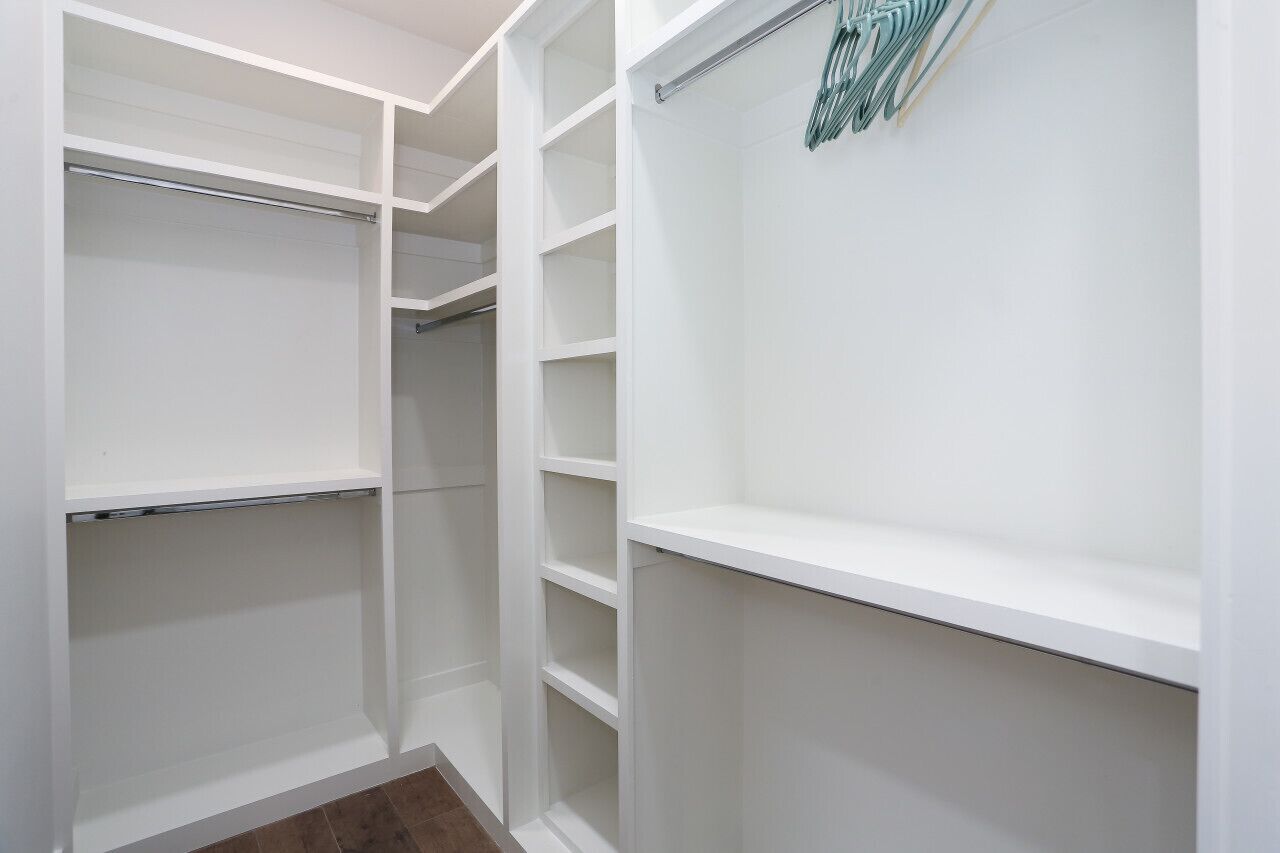 A white walk-in closet with multiple shelves and hanging rods.