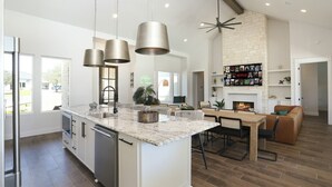 A spacious kitchen with a large island, pendant lights, and a fireplace.