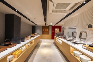 Un moderno hall de hotel con un pasillo central, mostrador de recepción y una puerta roja que da acceso al área de recepción.