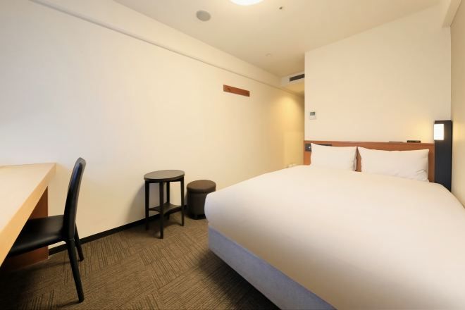Een hotelkamer met een bed, een bureau, een stoel en een klein tafeltje.