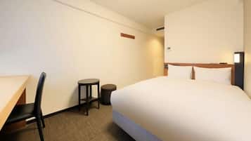Een hotelkamer met een bed, een bureau, een stoel en een klein tafeltje.
