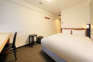 Una habitación de hotel con una cama, un escritorio, una silla y una mesita.