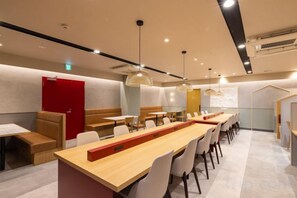 Un comedor moderno con mesas largas, sillas e iluminación colgante.