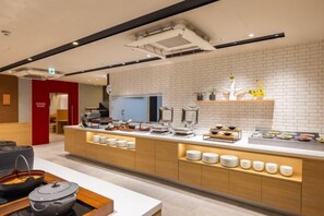 Een moderne keuken met een centraal eiland, een witte betegelde spatwand en diverse keukenapparaten.
