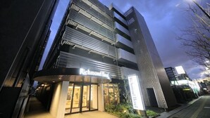 Un bâtiment moderne, sur lequel on peut lire l’inscription « Richmond Hotel », qui se distingue par son entrée imposante et sa façade verticale en verre.
