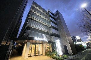 Un edificio moderno con un letrero que dice 'Richmond Hotel', destacando una entrada principal y una fachada de vidrio vertical.