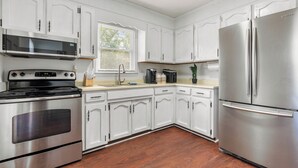 Una cucina moderna con mobili bianchi, elettrodomestici in acciaio inossidabile e pavimento in legno.