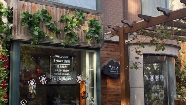 Een restaurant met een houten gevel, een welkomstbord en een menukaart in het raam.