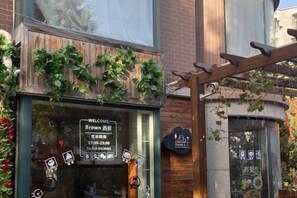 A restaurant with a wooden facade, a welcome sign, and a menu displayed on the window. - RJ Brown Hotel (Beijing)