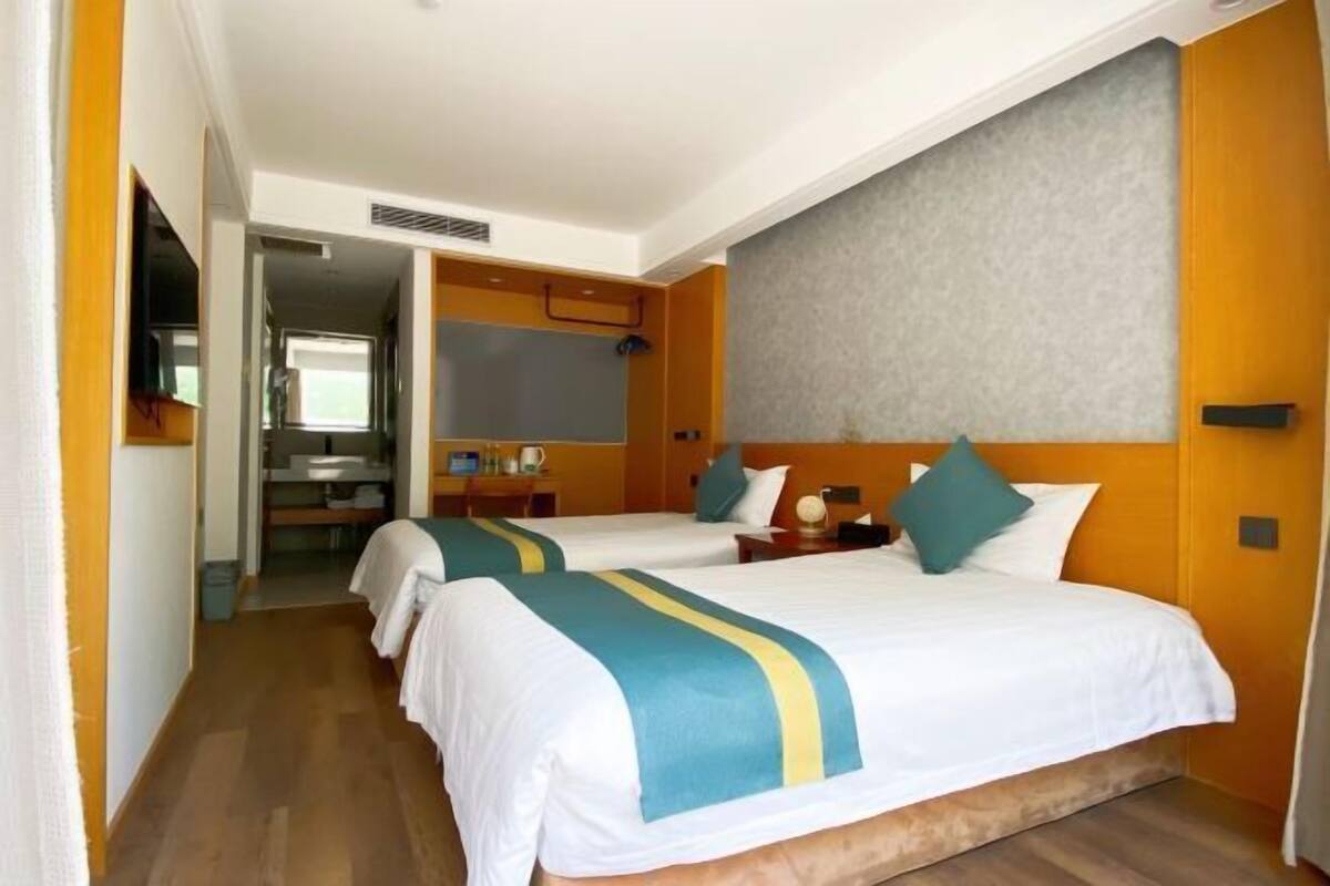 Habitación de hotel con dos camas, baño y kitchenette.