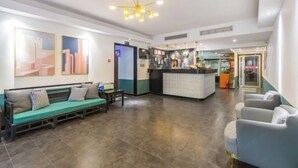 Een hotellobby met een receptiebalie, een zithoek en kunstwerken aan de muren.