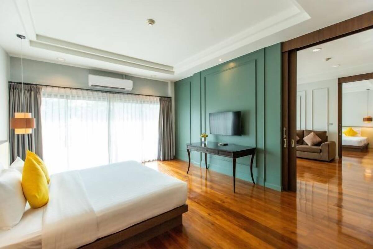 A hotel room with a bed, a TV, a desk, and a sofa.