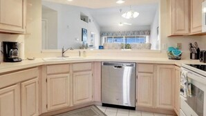 A modern kitchen with light wood cabinets, a stainless steel dishwasher, and a built-in oven. - " SPANISH WELLS GOLF & CC "     Chilled Pool for summer fun! (Bonita Springs)