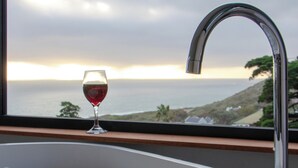 Eine Badewanne voller Blasen, ein Glas Rotwein und Blick aufs Meer durch ein Fenster.