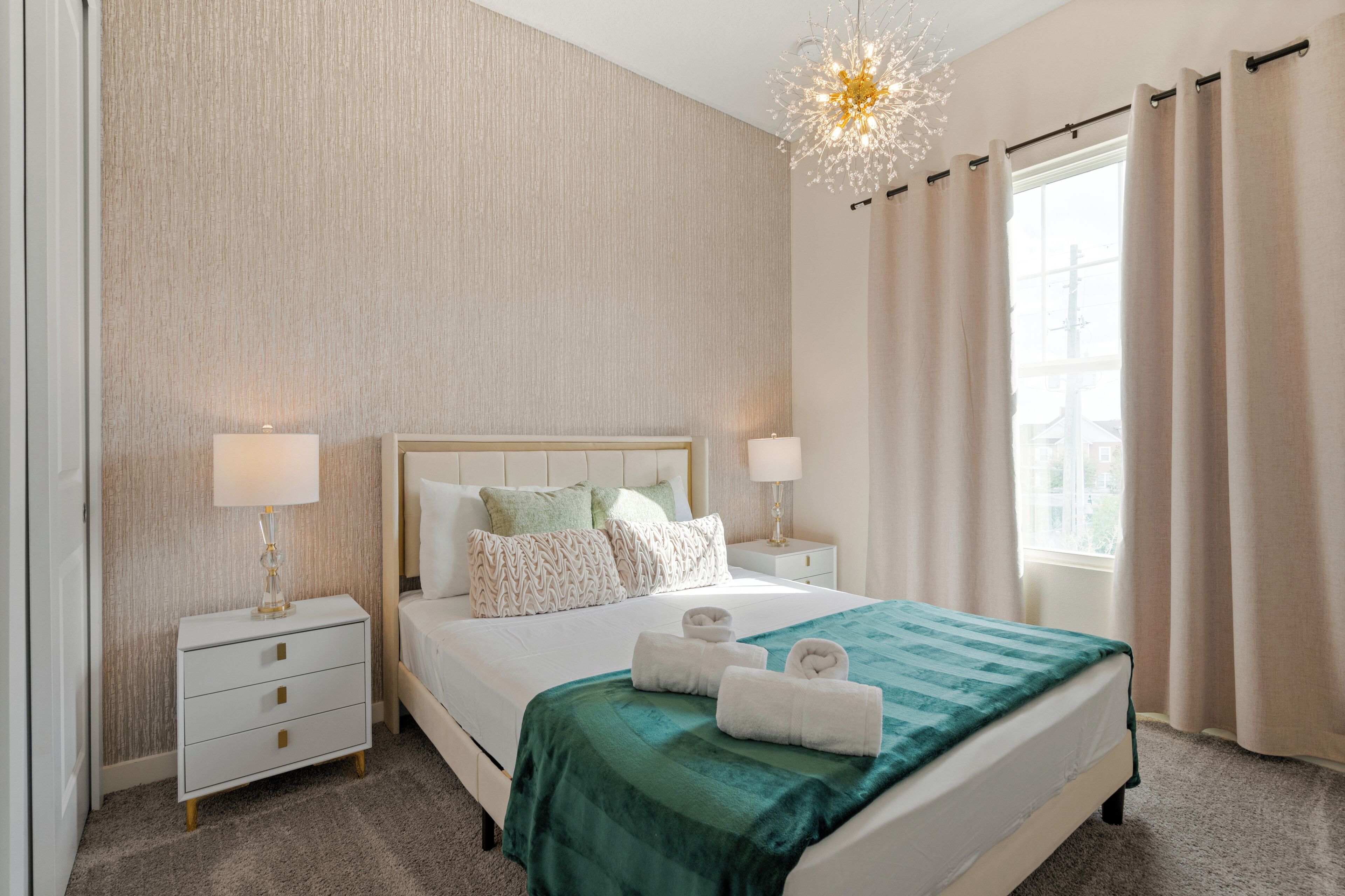 Ein ordentlich eingerichtetes Hotelzimmer mit einem großen Bett, zwei Nachttischen und einer Kronleuchter.