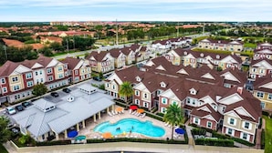 Un quartier résidentiel composé de plusieurs maisons à deux étages, d’une piscine et d’un espace de stationnement couvert.