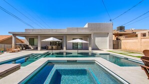 A modern house with a swimming pool, outdoor furniture, and a garage.