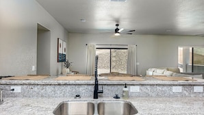 A modern kitchen with granite countertops, a double sink, and a ceiling fan.