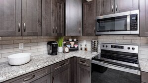 A modern kitchen with dark wood cabinets, a stainless steel microwave, and a built-in oven.