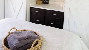 Een slaapkamer met een bed, een nachtkastje, een dressoir, een spiegel en een airconditioning.