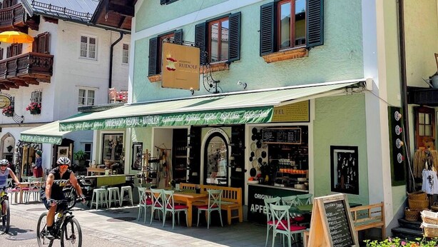 Restaurante con terraza, una señal y una bicicleta estacionada afuera.