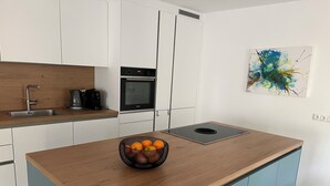 Una cocina moderna con armarios blancos, encimera de madera, horno empotrado y cafetera.
