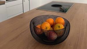 Una cocina con armarios blancos, un horno negro, una estufa de acero inoxidable y un bol de malla negra con naranjas sobre una encimera de madera.