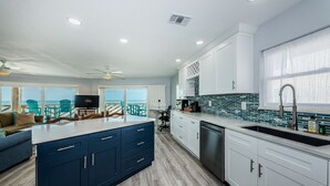 Una cocina moderna con una isla grande, armarios blancos y vistas al océano.